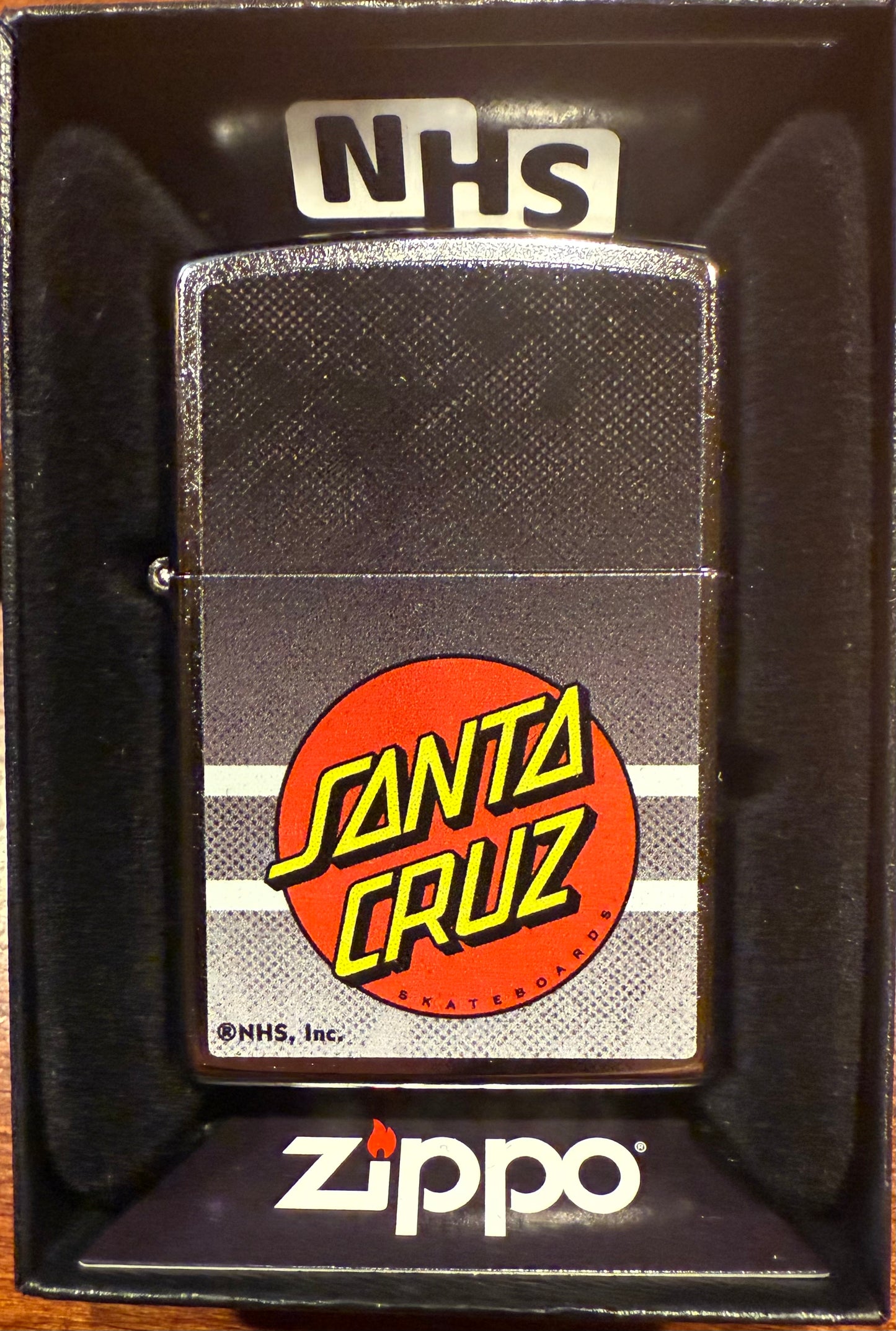 Zippo lighter with a black matte finish featuring the Santa Cruz Skateboards' iconic dot logo in color on the front.