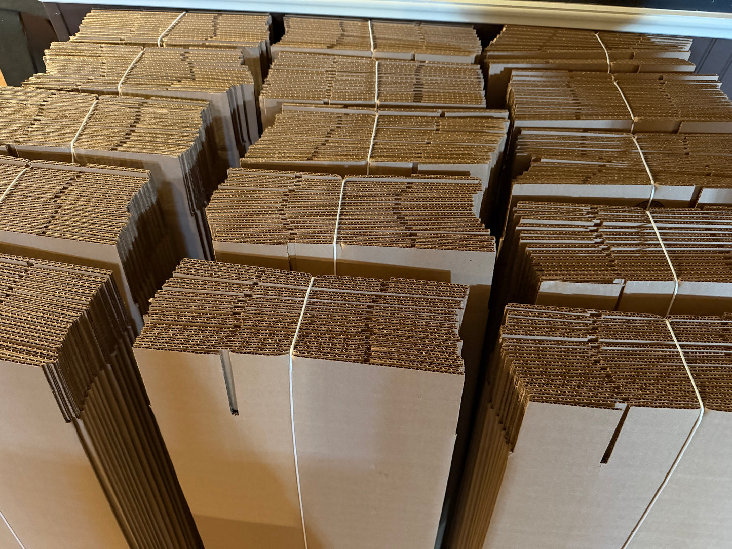 A stack of cardboard boxes designed to ship skateboard decks, showing the boxes' folded edges and the brown paper interiors.