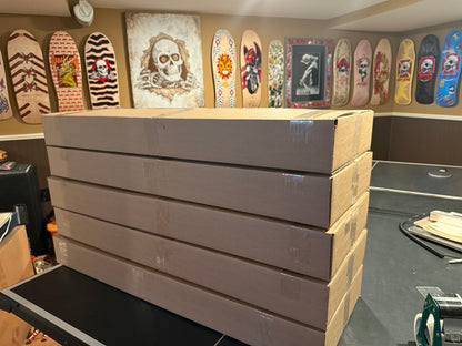 Stack of large brown boxes with skateboard decks displayed in front.