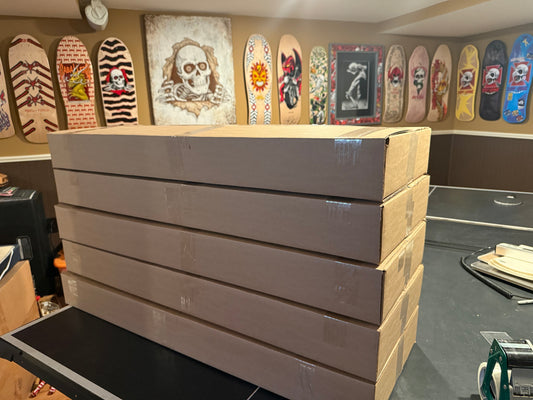 Stack of large brown boxes with skateboard decks displayed in front.