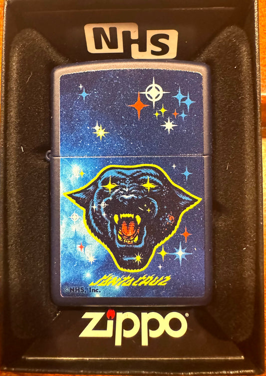 A Zippo lighter with a navy matte finish featuring a colorful front design with a panther head and stars. The lighter is packaged in a box with 'NHS' and 'Santa Cruz Skateboards' branding.  Asta Cat Zippo.